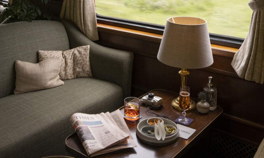 Barwagen mit einem grünen Sofa und Getränken auf dem Tisch. | © belmond.com/The World from a Window