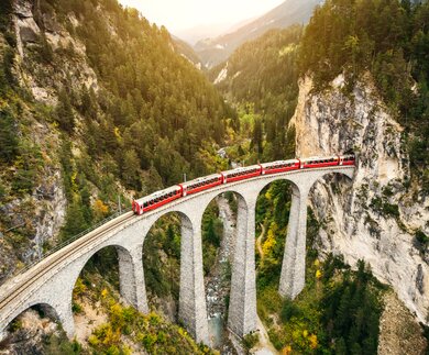 Im Panoramawagen des Bernina Expresses auf dem Landwasserviadukt im Herbst in der Schweiz | © Gettyimages.com/nikada