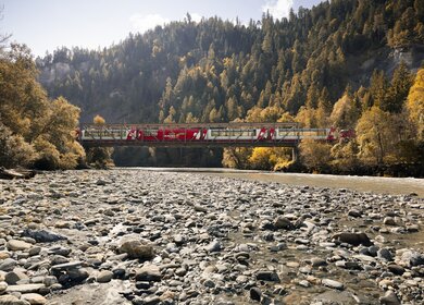 Der Glacier Express fährt über eine Brücke in der Rheinschlucht in der Schweiz im Herbst | © Glacier Express AG/Stefan Schlimpf
