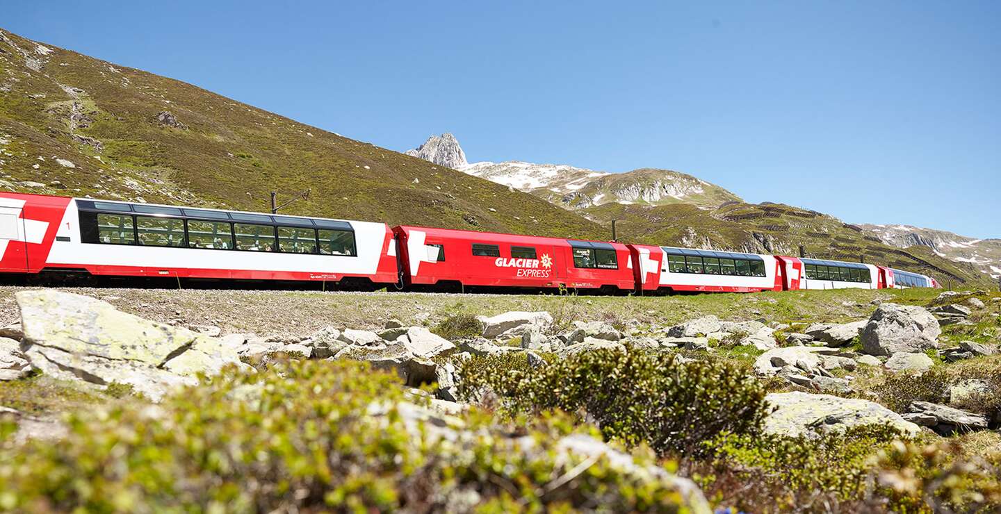 Der Glacier Express fährt über den Oberalppass in den Schweizer Alpen im Frühling | © Glacier Express AG/Stefan Schlumpf