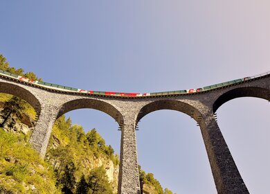 Der Glacier Express faehrt auf dem Landwasserviadukt in der Schweiz im Herbst | © Glacier Express AG/Stefan Schlimpf