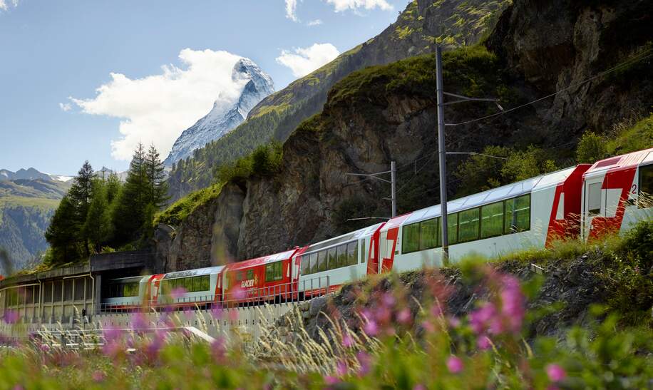 Der Glacier Express faehrt durch Zermatt in der Schweiz im Fruehling | © Glacier Express AG/Stefan Schlimpf