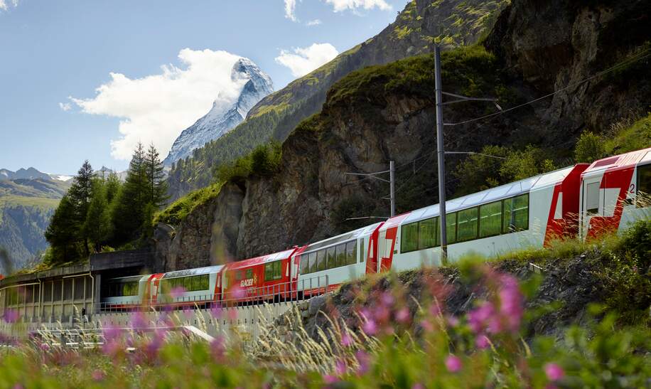 Der Glacier Express fährt durch Zermatt in der Schweiz im Frühling | © Glacier Express AG/Stefan Schlimpf