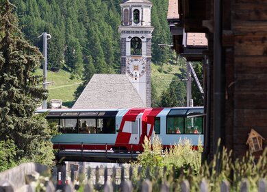 Der Glacier Express faehrt durch Bever in der Schweiz | © Glacier Express AG/Stefan Schlimpf