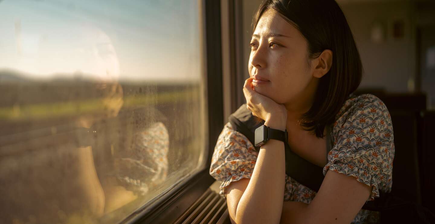 Asiatische Frau schaut nachdenklich aus dem Zugfenster | © Gettyimages.com/recep-bg