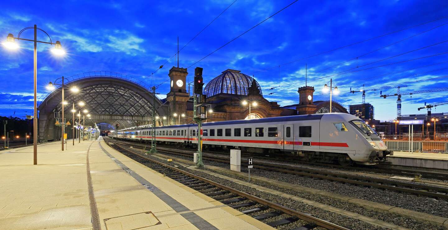 einen Bahnhof bei Daemmerung mit einem einfahrenden oder abfahrenden Zug und einer großen Glasdachkonstruktion. | © Deutsche Bahn AG