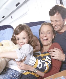 Laechelnde vierkoepfige Familie im Zug, die die Fahrt geniessen | ©  Deutsche Bahn AG