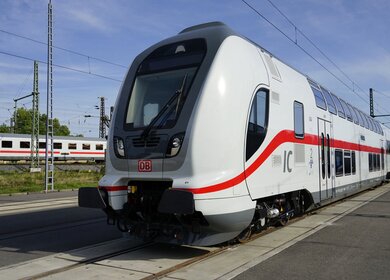 einen modernen weißen und grauen Zug der Deutschen Bahn mit roten Akzenten, der an einem Bahnhof steht. | © Deutsche Bahn AG