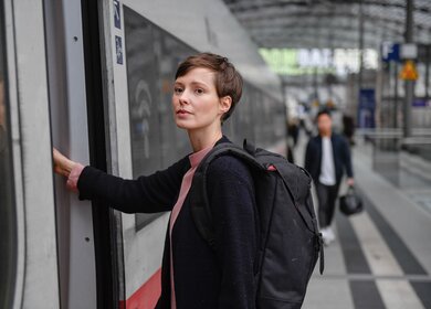 Junge Frau mit kurzen Haaren und Rucksack steigt am Bahnhof in einen ICE | © Deutsche Bahn AG/Max Lautenschläger