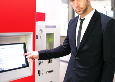 Reisender bedient ein Display und kauft ein Bahnticket am Fahrkartenautomaten | © Gettyimages.com/franckreporter