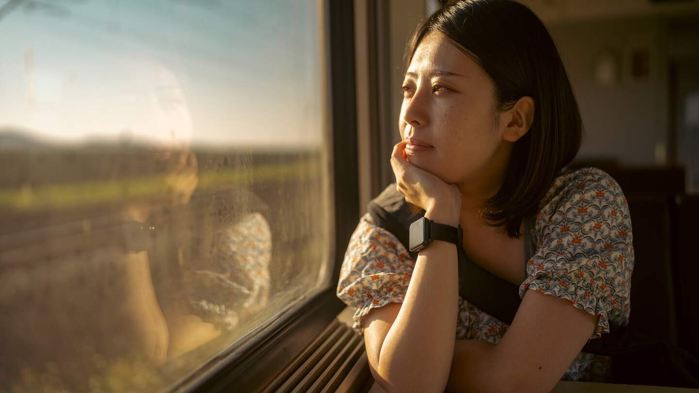 Asiatische Frau schaut nachdenklich aus dem Zugfenster | © Gettyimages.com/recep-bg