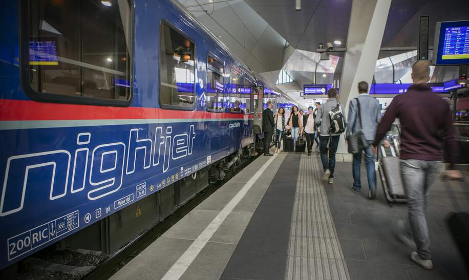 Blick auf einen Wagon des ÖBB Nightjets der neuen Generation am Bahnhof mit vorbeilaufenden Fahrgaesten  | © ÖBB/Harald Eisenberger