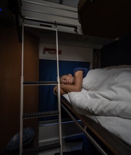 Frau schläft im Schlafwagen eines Nachzugs | © Gettyimages.com/amirphoto