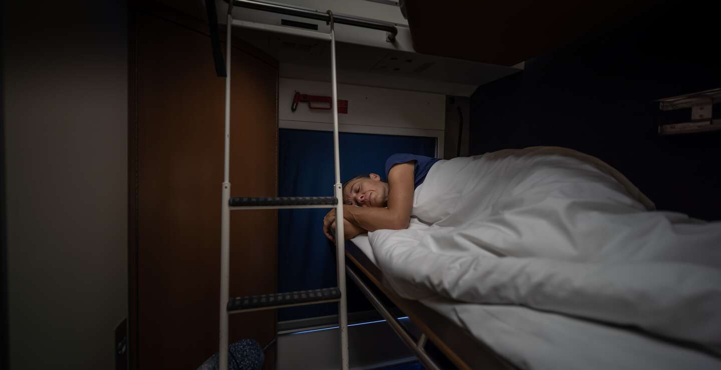 Frau schläft im Schlafwagen eines Nachzugs | © Gettyimages.com/amirphoto