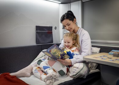 Eine Frau liegt mit ihrem Kind in dem Bett des Liegewagens des ÖBB Nightjets der neuen Generation | © ÖBB/Harald Eisenberger