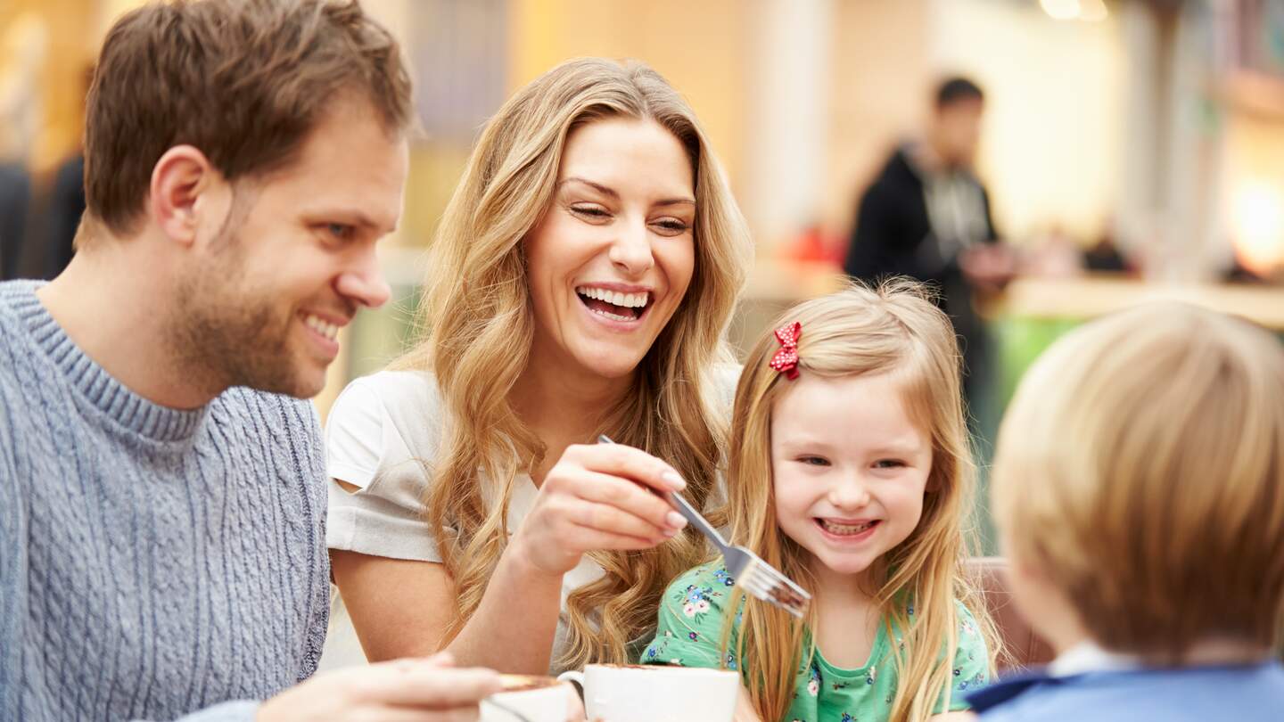 Familie - bestehend aus Mutter, Tochter, Vater, Sohn - geniessen Kuchen im Café zusammen  | © Gettyimages.com/monkeybusinessimages