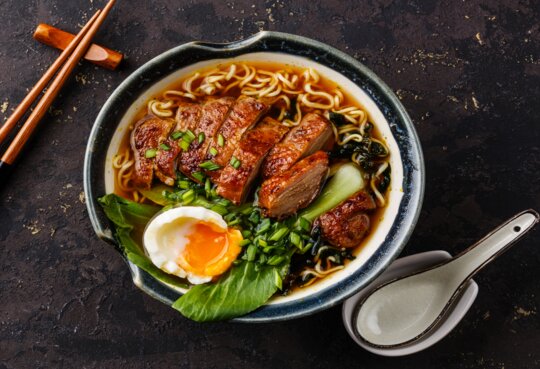 Ente Nudeln mit Ei und Pak Choi Kohl in Schüssel auf dunklen schwarzen Stein Hintergrund | © gettyimages.com/Lisovskaya