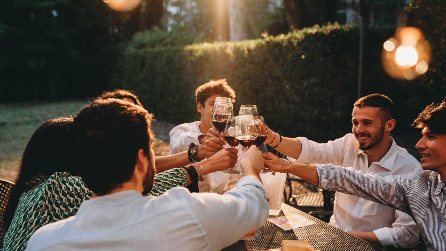 Freunde stossen beim Abendessen gemeinsam an | © Gettyimages.com/filippobacci