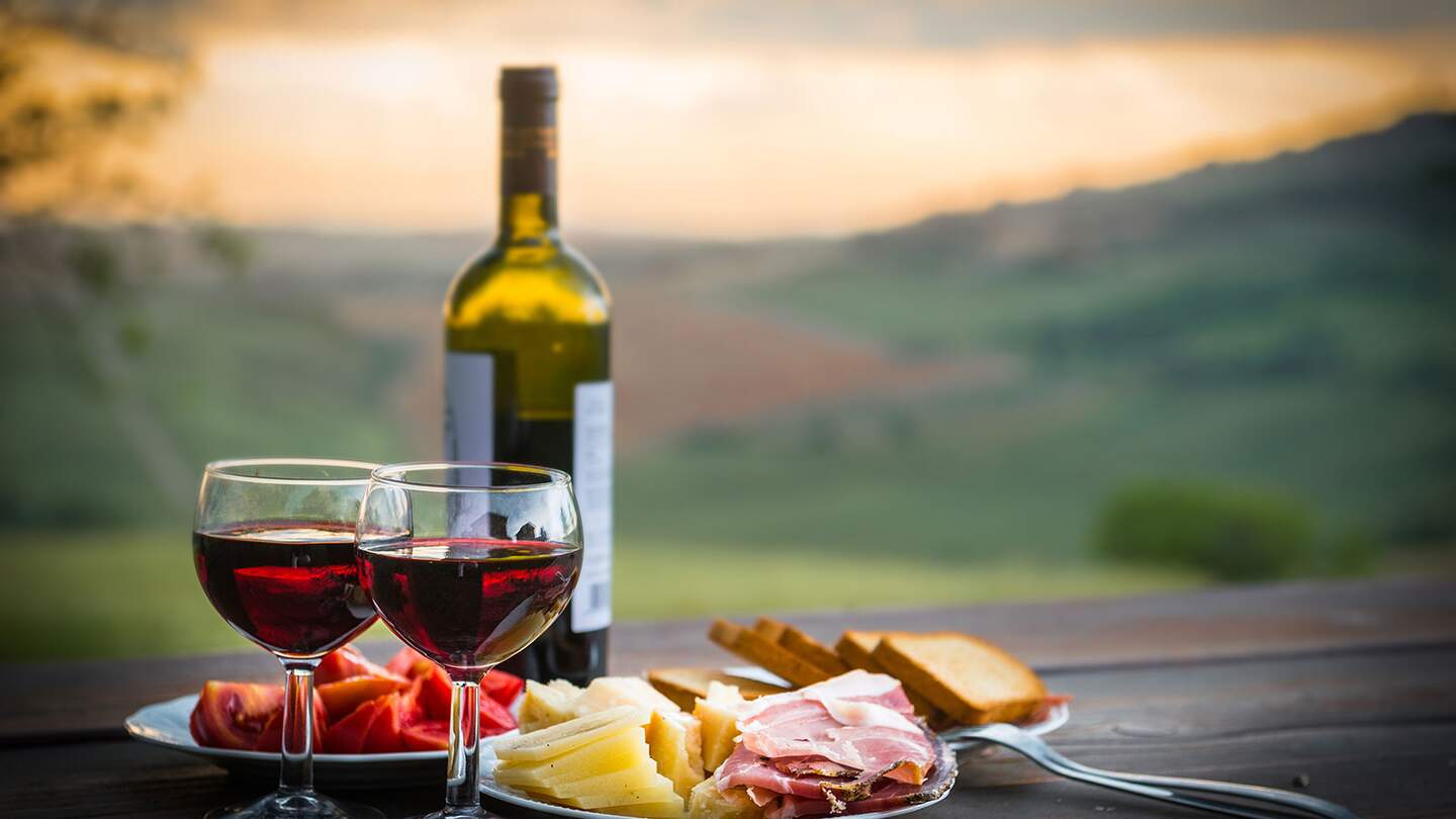 Stillleben Rotwein, Kaese und Schinken vor verschwommenem Hintergrund | © Gettyimages.com/scorpp