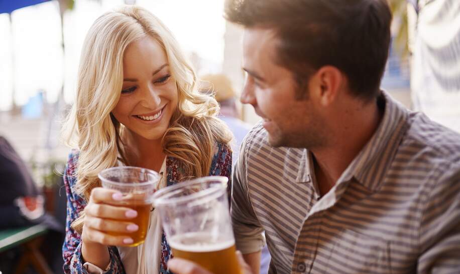 Paar, das Bier in Plastikbechern an der Bar im Biergarten | © Gettyimages.com/rez-art