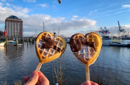 Hamurger Hafen an der Elbe. Zwei Herzwaffeln am Stil werden gehalten. | © Gettyimages.com/lapasmile