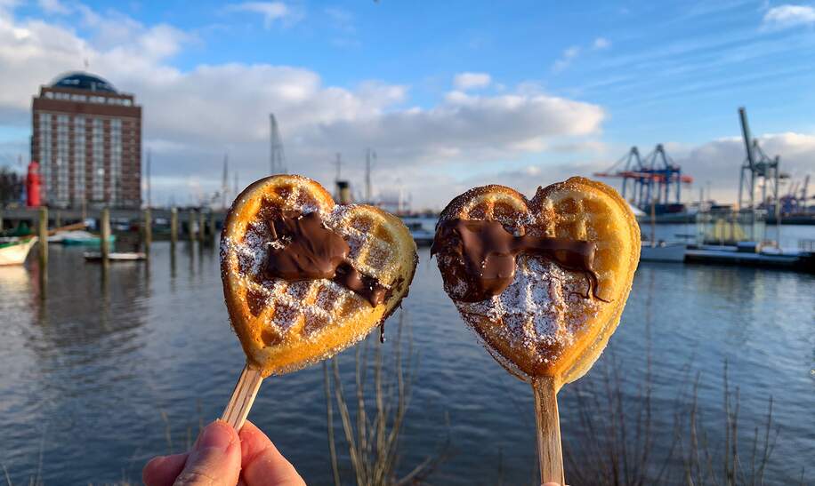 Hamurger Hafen an der Elbe. Zwei Herzwaffeln am Stil werden gehalten. | © Gettyimages.com/lapasmile