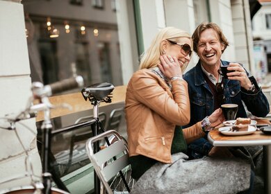 Paar trinkt Kaffe und ist Kuchen an einem Tisch im Assenbereich eines Cafès | © Gettyimages.com/Geber86