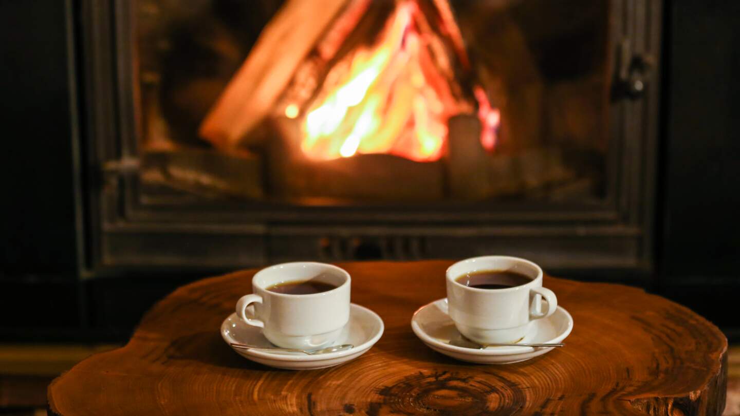 Zwei Kaffeetassen vor dem lodernden Kamin | © Gettyimages.com/Burak Sür