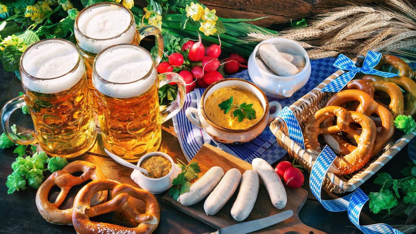 Bayerische Wurst mit Brezeln, süßem Senf und Bierkrüge auf rustikalen Holztisch | © Gettyimages.com/Alexander Raths