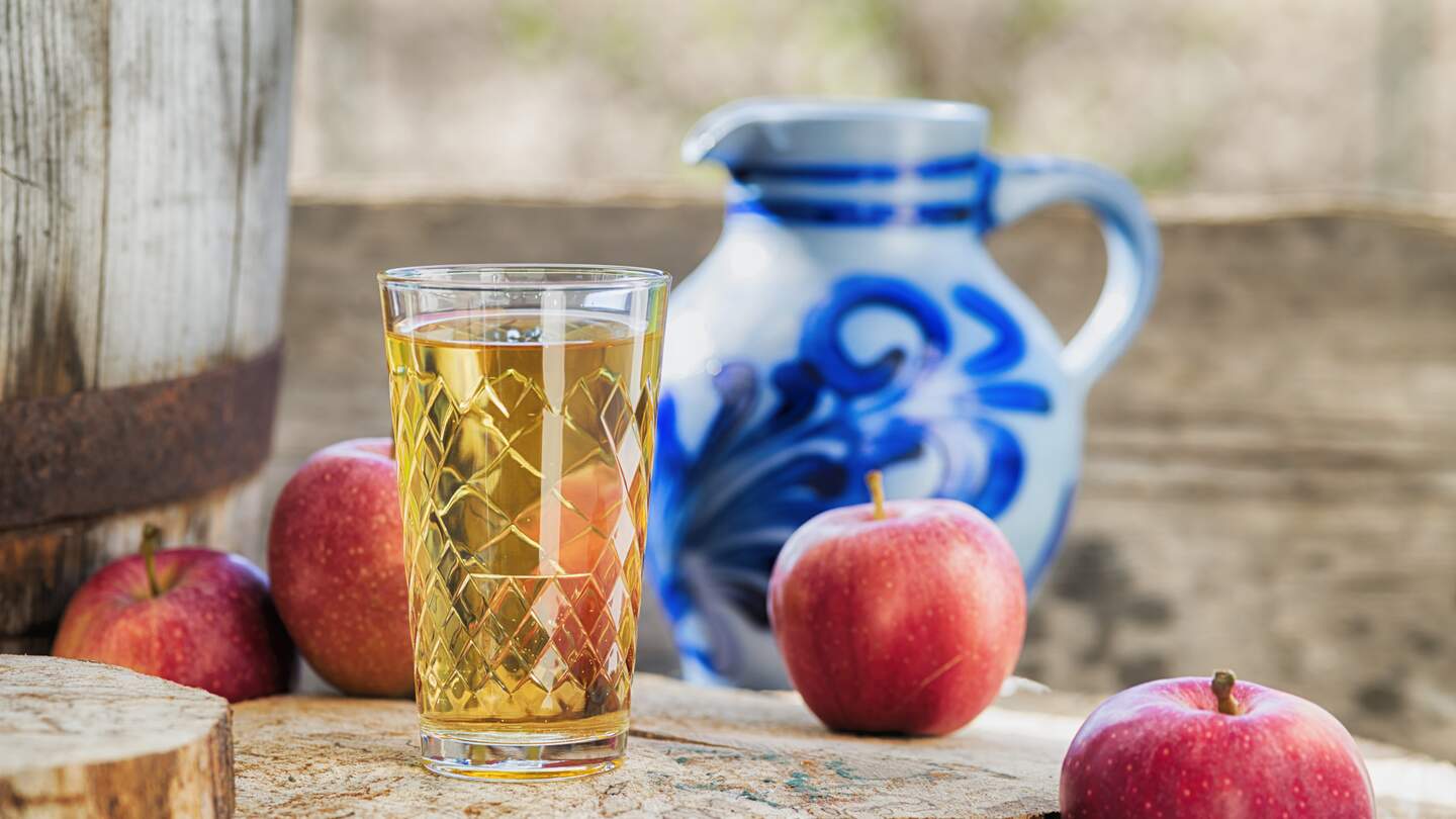 Traditioneller hessischer Apfelwein oder Apfelsaft vor dem traditionellen Tonkrug alias Bembel. Hölzerner Hintergrund. | © Gettyimages.com/kontrast-fotodesign