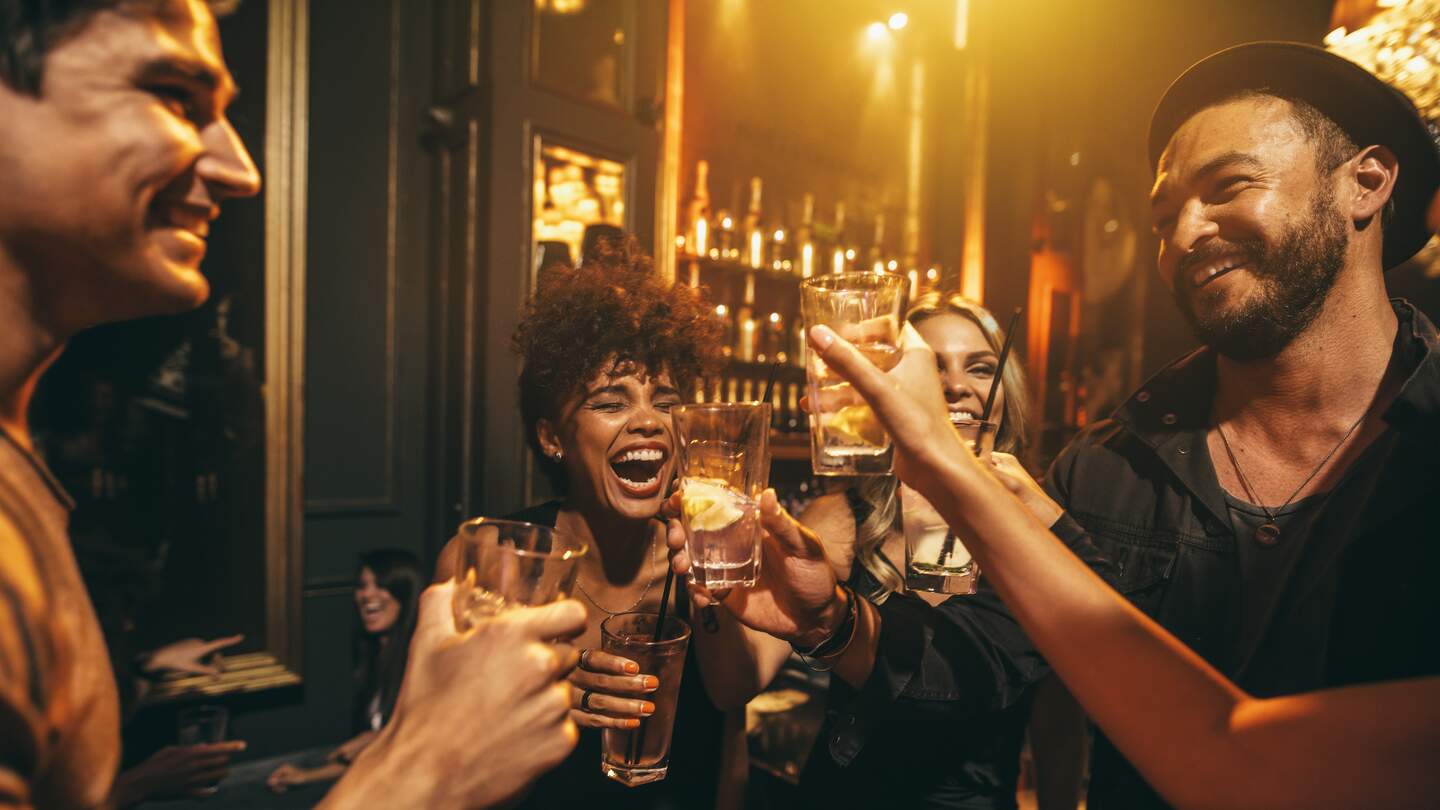 Junge Maenner und Frauen geniessen eine Party und trinken Cocktails in einem Nachtclub | © Gettyimages.com/jacoblund