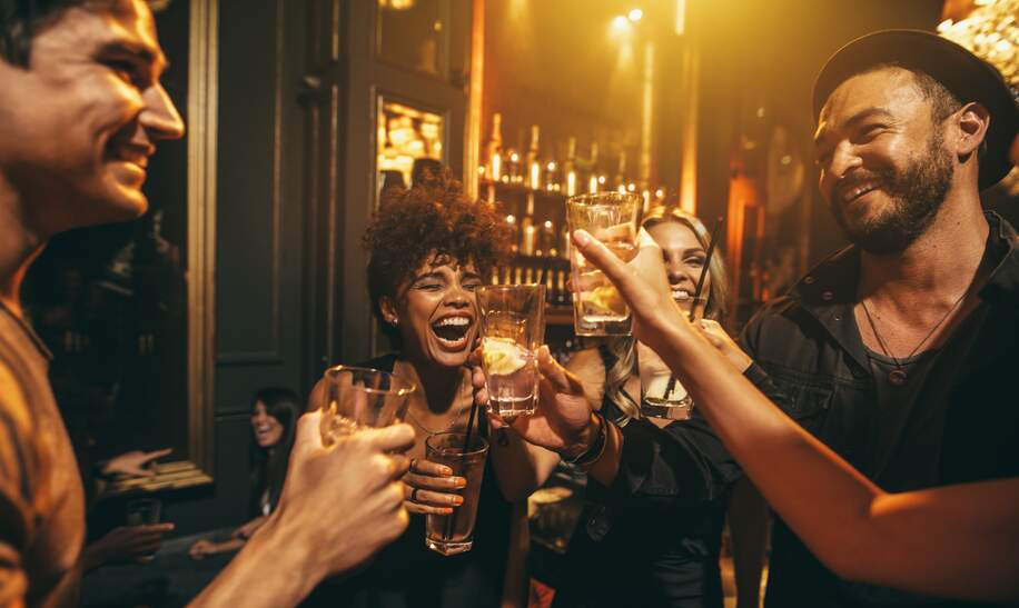 Junge Maenner und Frauen geniessen eine Party und trinken Cocktails in einem Nachtclub | © Gettyimages.com/jacoblund