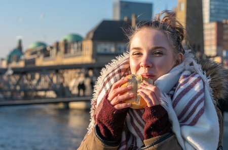 Eine Frau geniesst ein Fischbroetchen im Hamburger Hafen | © Gettyimages.com/Jens Rother
