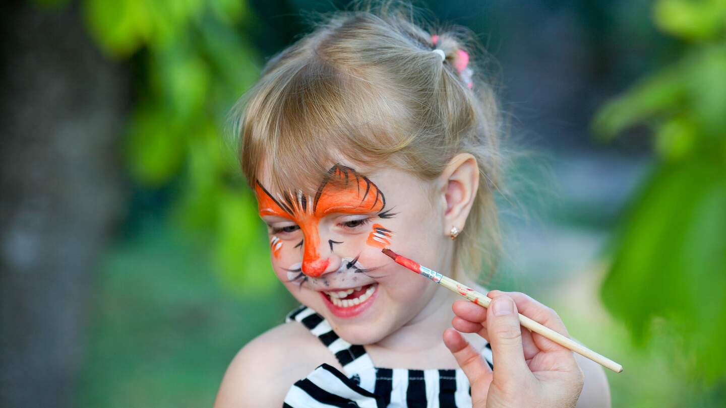 Einem glücklichen Mädchen wird das Gesicht angemalt | © Gettyimages.com/irinatiumentseva