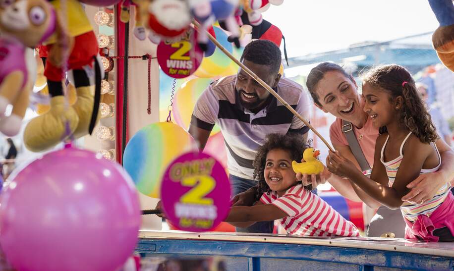 Sie spielen zusammen Entenfang und die Mutter gratuliert ihrer Tochter, nachdem sie erfolgreich eine Ente gefangen hat, um einen Preis zu gewinnen. | © Gettyimages.com/solstock