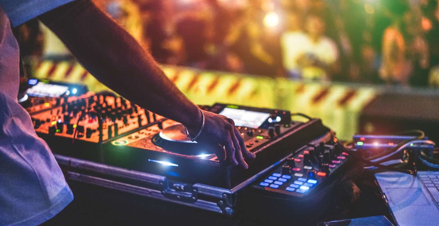 Dj Mixing Outdoor beim Silvester-Partyfestival mit Menschenmassen im Hintergrund | © Gettyimages.com/disobeyart