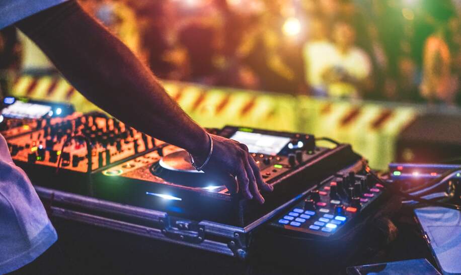 Dj Mixing Outdoor beim Silvester-Partyfestival mit Menschenmassen im Hintergrund | © Gettyimages.com/disobeyart