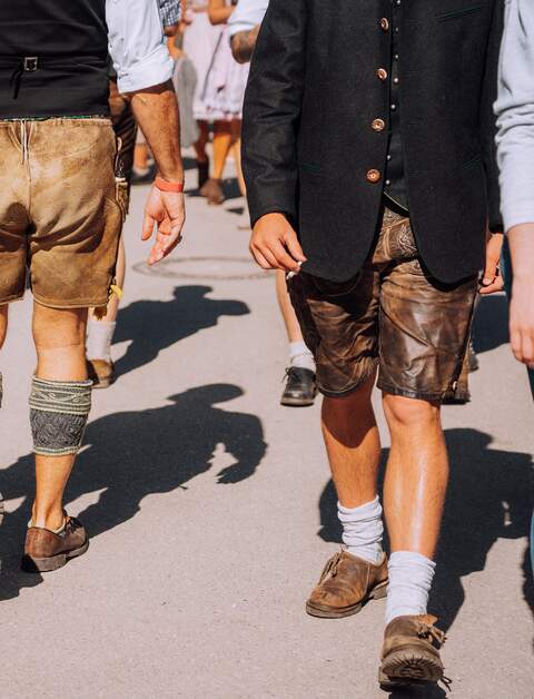 Zu sehen sind die Unterkoerper von Herren in traditionellen Lederhosen, Socken und Schuhe, die zu einer Tracht gehoeren | © Gettyimages.com/Nikada
