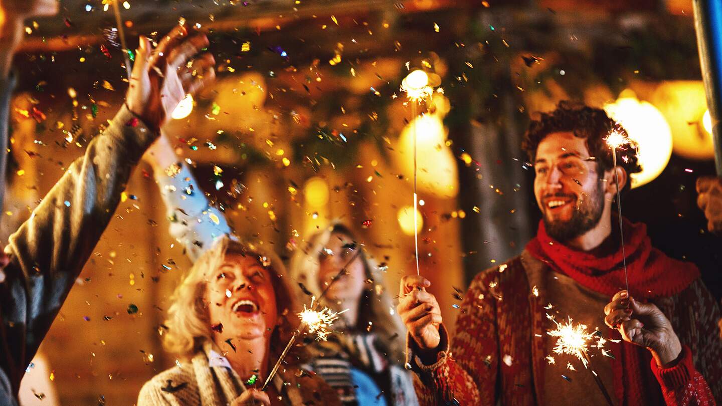 Eine Familie tanzt und feiert Silvester im Freien. | © Gettyimages.com/AjaKoska