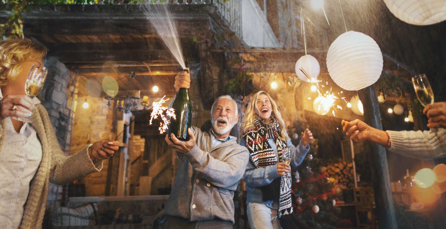  Ein älterer Mann oeffnete eine weitere Flasche Champagner und spritzte sie. | © Gettyimages.com/AjaKoska