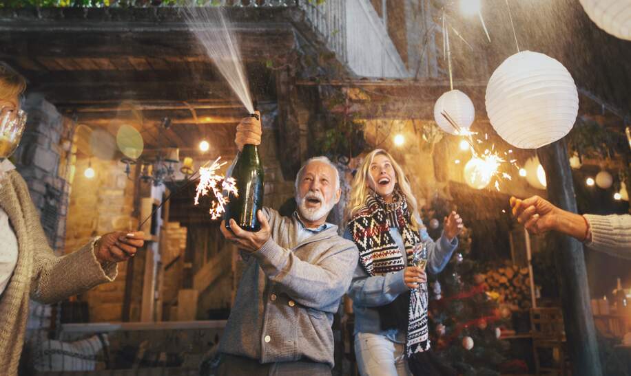  Ein älterer Mann oeffnete eine weitere Flasche Champagner und spritzte sie. | © Gettyimages.com/AjaKoska