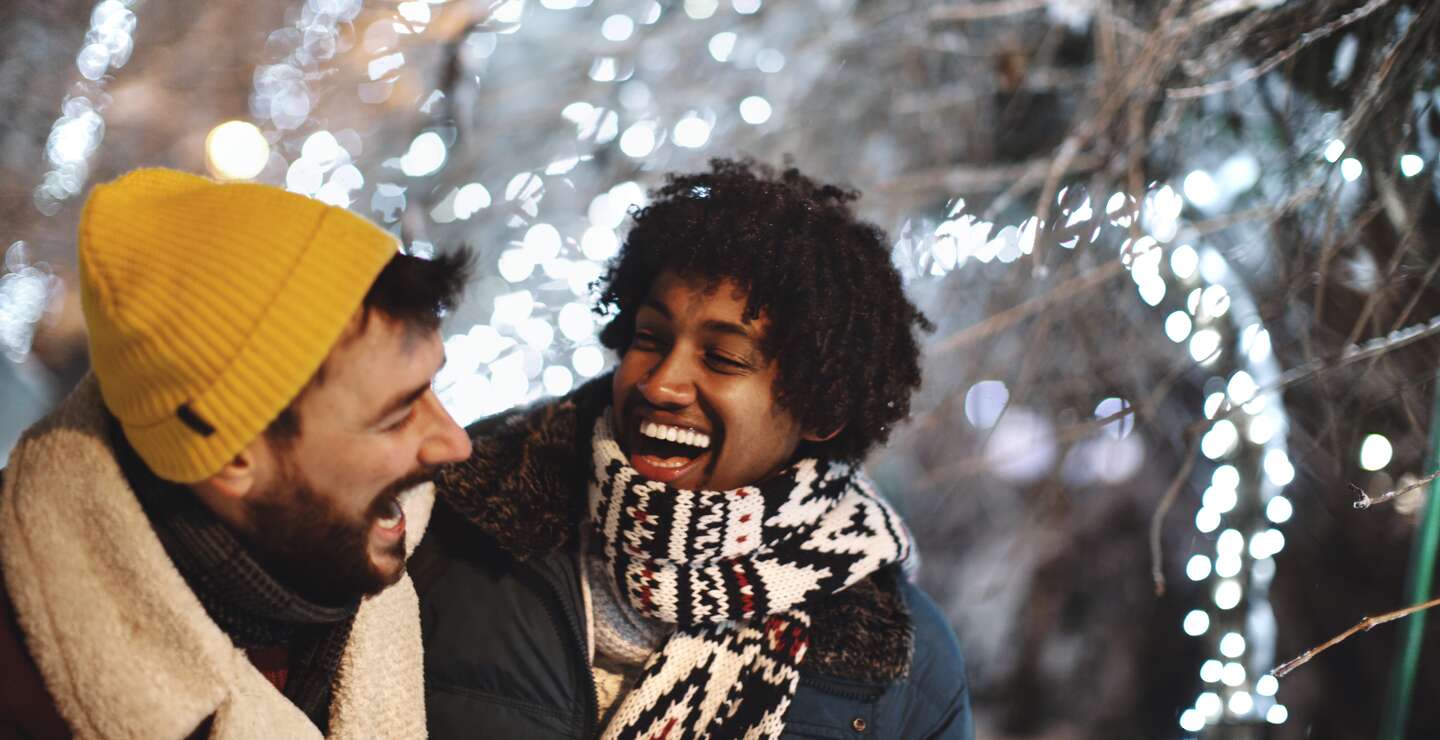 junge maennliche Freunde, die sich in der Silvesternacht im Freien umarmen und lachen. | © Gettyimages.com/Aja Koska