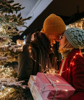 Foto eines romantischen Paares mit Weihnachtsgeschenken im Freien | © Gettyimages.com/AleksandarNakic