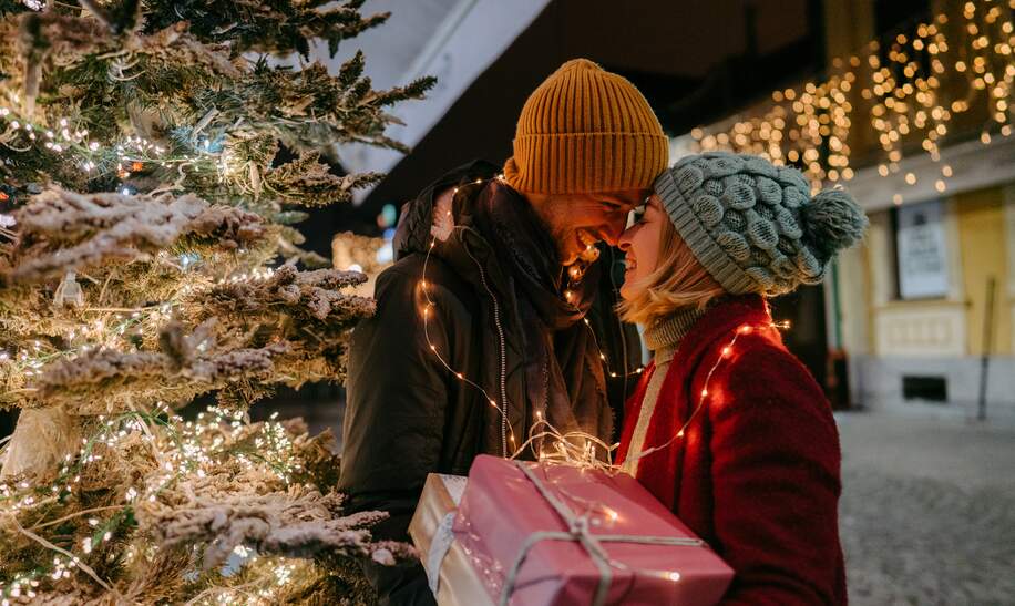 Foto eines romantischen Paares mit Weihnachtsgeschenken im Freien | © Gettyimages.com/AleksandarNakic