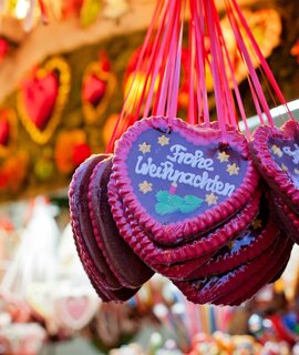 Markstand auf dem Weihnachtsmarkt und Lebkuchen Herzen | © Gettyimages.com/alethia97