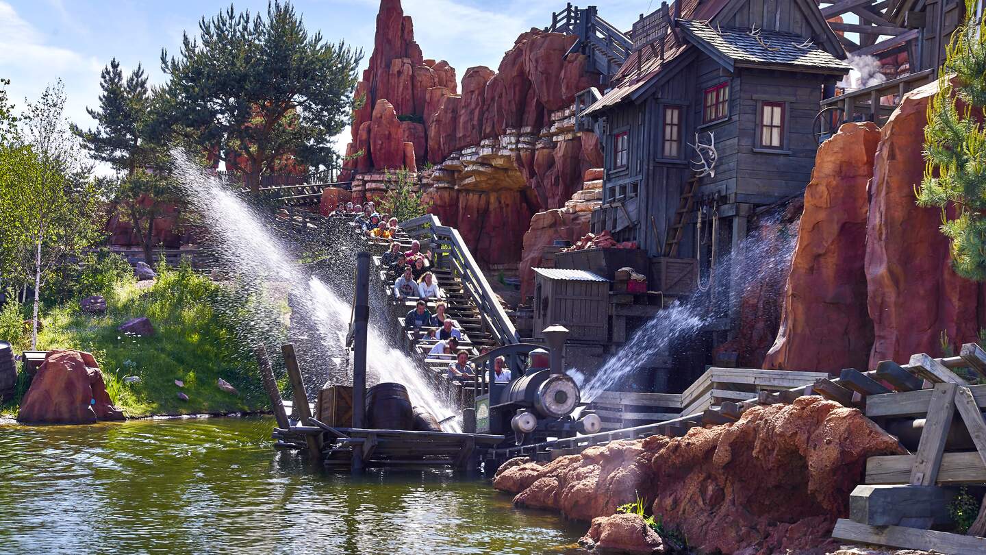 Die Attraktion "Big Thunder Mountain". Personen sitzen in einem Zug und fahren einen Hang herunter. | © Disney