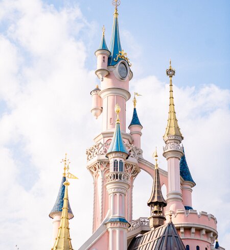 Das pinke Schloss Sleeping Beauty Castle in Disneyland Paris mit blau strahlendem Himmel | © Disney