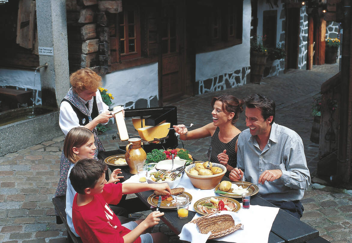 Eine Familie ist im Schweizer Restaurant im Europa-Park Käse Racelette | © Europa-Park