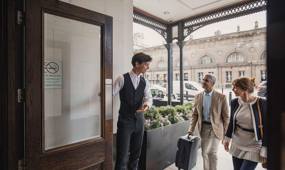 Der Portier des Hotels empfaengt ein älteres Paar fuer einen Wochenendtrip | © Gettyimages.com/SolStock