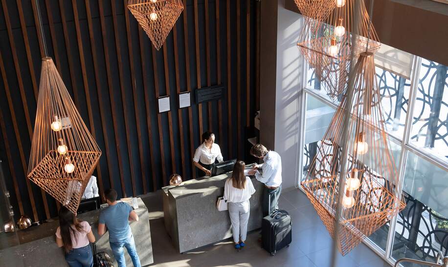 Gruppe von Reisenden checken an der Rezeption eines Luxushotels ein | © Gettyimages.com/Hispanolistic